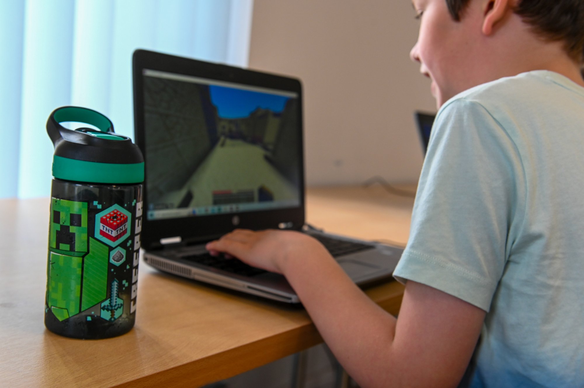 student at laptop on minecraft with minecraft water bottle